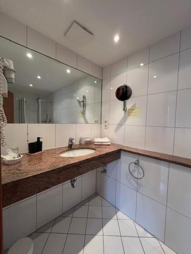 a bathroom with a sink and a large mirror at Classic Hotel Kaarst in Kaarst