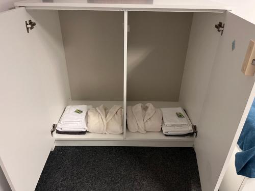 a white closet with white towels on a shelf at GIRLSTEL Wrocław - Girls ONLY Space in Wrocław
