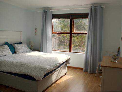 a bedroom with a bed and a large window at Sea Urchin in Gordonʼs Bay