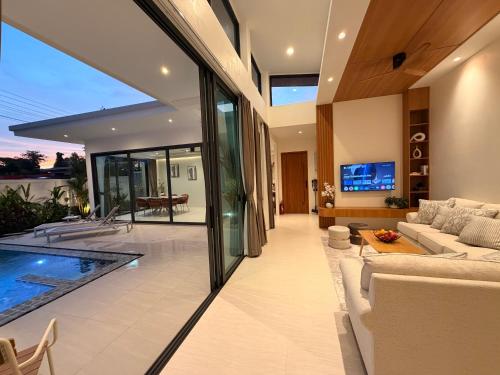 a living room with a couch and a swimming pool at Chareen Pool Villa in Ban Khlong Haeng