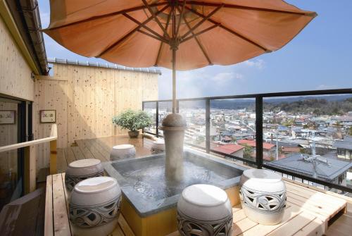 a hot tub on a balcony with an umbrella at Hoshokaku in Takayama