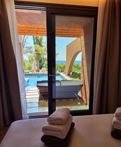 a bedroom with a view of a pool and a bed with towels at Euphoria Villa, 9 bdrs with private pools, beachfront in Kalogria