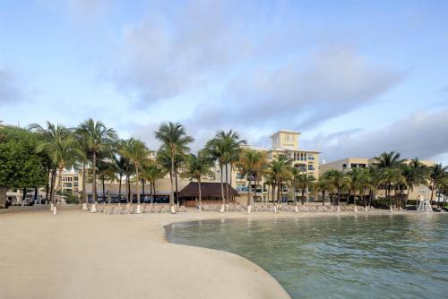 a beach with palm trees and a hotel in the background at Occidental Costa Cancún - All Inclusive in Cancún