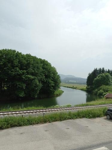a river with a car parked next to a road at Le moulinot in Morteau