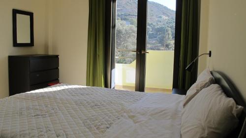 a bedroom with a bed and a large window at Artemis Appartments in Pitsidia