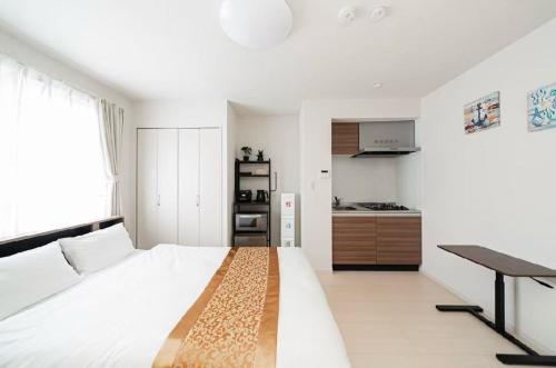a white bedroom with a large bed and a desk at Tsukimi Inn Shinkoiwa in Tokyo