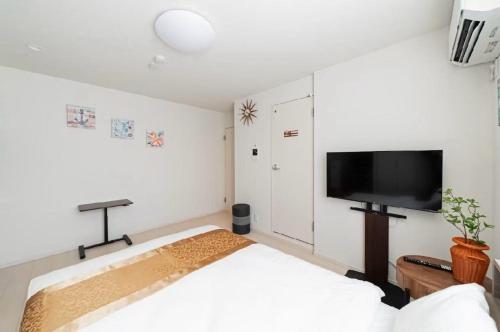 a bedroom with a bed and a flat screen tv at Tsukimi Inn Shinkoiwa in Tokyo