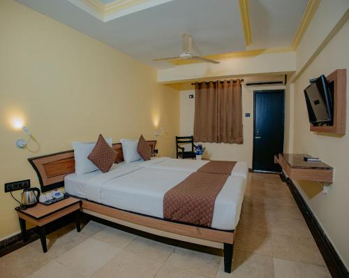 a bedroom with a large bed and a television at Om Shiv Hotel Formerly The Treat Hotel in Madgaon