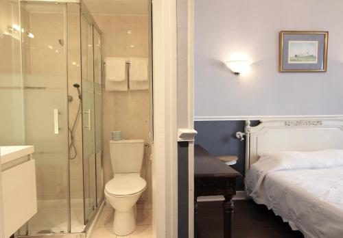 a bathroom with a toilet and a shower and a bed at Hôtel Chopin in Paris