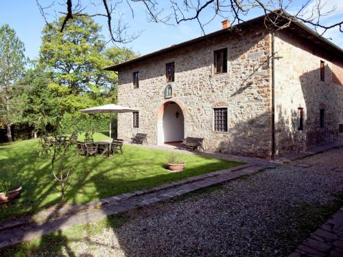un antiguo edificio de piedra con una mesa y un patio en Serene Apartment with Garden Pool Terrace Deckchairs en Lucolena in Chianti