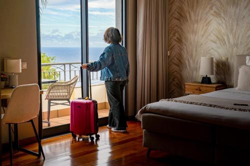 a woman standing in a hotel room with a suitcase at Casa do Mundo Madeira in Gaula