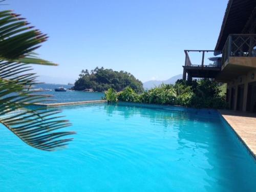 a large blue swimming pool next to a house at Magnífica Costeira in Ilhabela