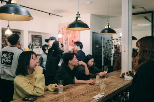 a group of people sitting at a table in a restaurant at Public Guest House in Karuizawa