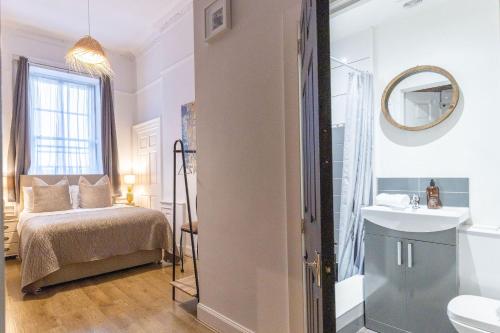 a bedroom with a bed and a sink and a mirror at 38 Bide Collective in Edinburgh