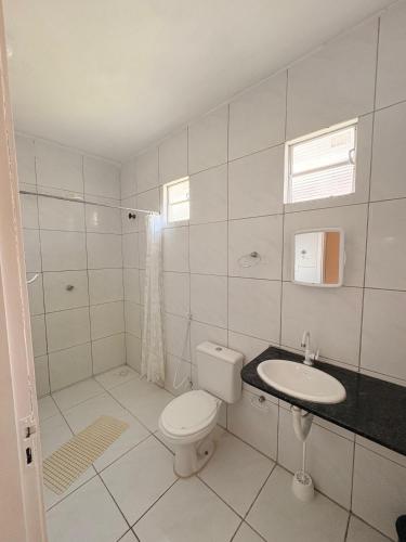 a white bathroom with a toilet and a sink at Caponga Beach House - 100m da Praia in Cascavel