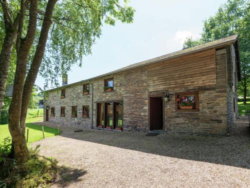 a stone barn with a tree in front of it at Quaint Cottage In Jevign with Terrace in Lierneux