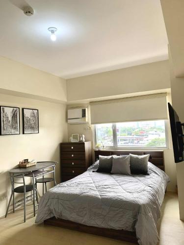 a bedroom with a bed and a table and a window at Atria Condo in Iloilo City