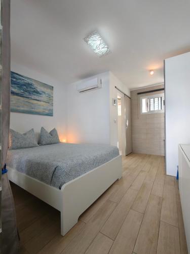 a white bedroom with a bed and a wooden floor at BLU in Puerto del Carmen