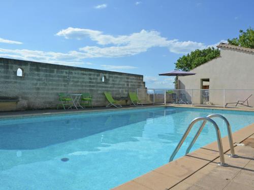 a large swimming pool with chairs and an umbrella at Villa in Saint Privat de Champclos with pool in Barjac