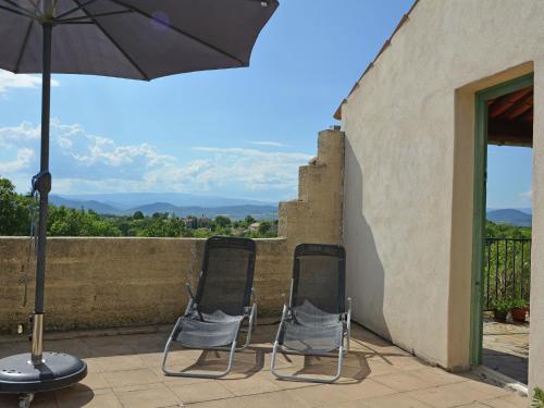 two chairs sitting on a patio with an umbrella at Villa in Saint Privat de Champclos with pool in Barjac