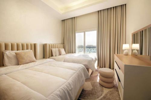 a hotel room with two beds and a television at Silk Valley – Beachfront 3BR near Al Hamriyah in Sharjah