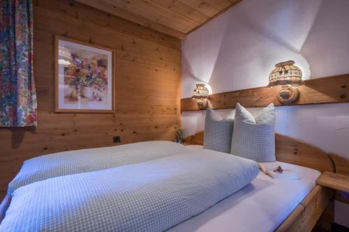 a bedroom with a white bed with wooden walls at Aparthotel Gallahaus in Zell am Ziller