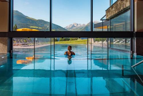 a person in a swimming pool with mountains in the background at Gut Sonnberghof in Mittersill