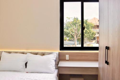 a bedroom with a window and a bed with white pillows at Mui Da Hotel in Phan Thiet