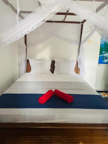 a bed with two red pillows on it at Ocean Breeze in Dickwella