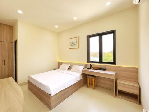a bedroom with a bed and a desk and a window at Mui Da Hotel in Phan Thiet