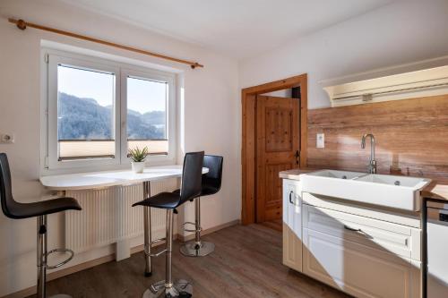 a kitchen with a sink and two bar stools at Harry's Hittn in Söll