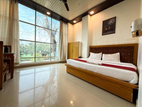 a bedroom with a large bed and a large window at AARYA Corbett Resort & SPA - 8 minutes drive to Kosi River in Nainital