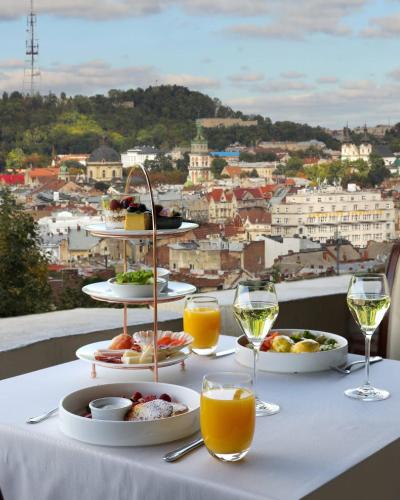 a table with plates of food and glasses of wine at Citadel - Gastro Boutique Hotel- Готель Цитадель Львів in Lviv