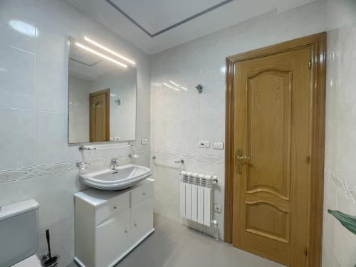 a white bathroom with a sink and a mirror at A DE NENO in Melide