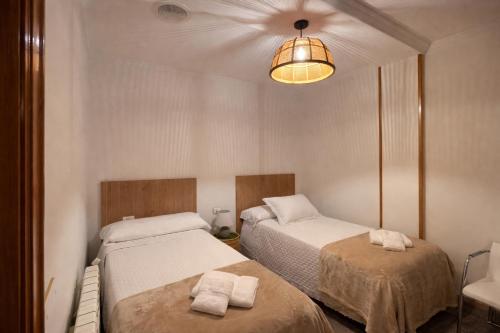 a bedroom with two beds and a light fixture at A DE NENO in Melide