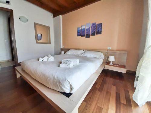 a large white bed in a room with wooden floors at Sakura House By Bookinggardalake in Moniga