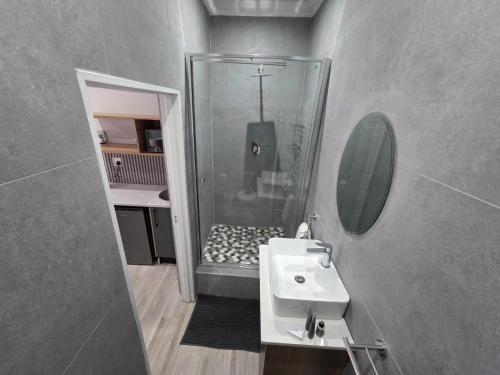 a small bathroom with a sink and a shower at Alte Welkom Guesthouse in Klerksdorp