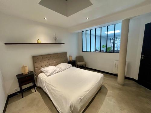 a bedroom with a white bed and a large window at Logis Hotel du Maine in Laval