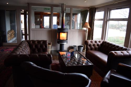 a living room with two leather couches and a table at Briarfields Hotel in Titchwell