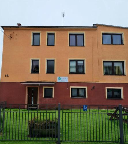 an orange building with black windows and a fence at Margaretka in Łeba