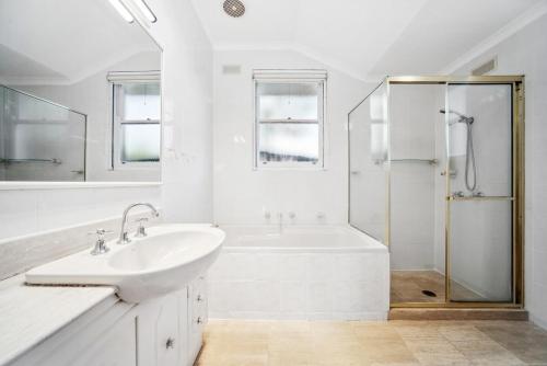 a white bathroom with a sink and a shower at Fairlight Luxe Escape 4BR with Parking in Killara