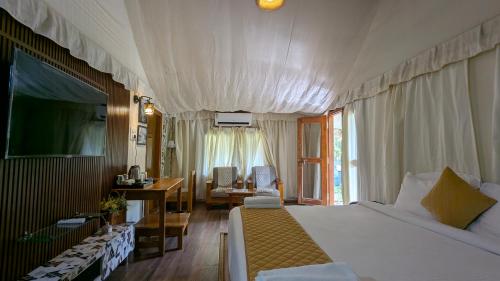 a bedroom with a bed and a desk and a television at Advaya Luxury Resort, Sakleshpur in Sakleshpur