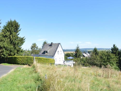 a white house on a hill next to a road at Peaceful Holiday Home in Rascheid near Forest in Geisfeld