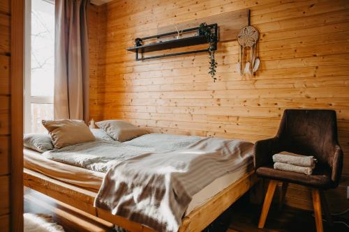 a bed and a chair in a room with wooden walls at Tiny house v Moravském Berouně in Moravský Beroun