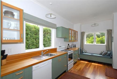 a kitchen with green and white cabinets and two windows at One Panama in Martinborough 