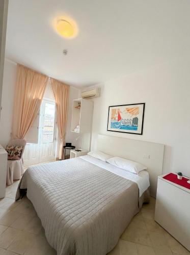 a bedroom with a large white bed and a window at Ortigia Mastrarua rooms in Syracuse