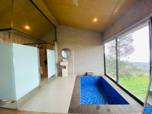 a bathroom with a blue tub with a large window at Azana Essence Selo Boyolali in Boyolali