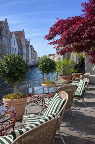 a row of chairs and tables next to a river at Hotel Van Cleef in Bruges