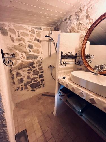 a stone bathroom with a sink and a mirror at Aube du Tilleul in Lagorce