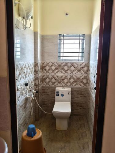 a bathroom with a toilet and a window at Kalpatharu Sprit Boarding and Lodging in Sivaganga